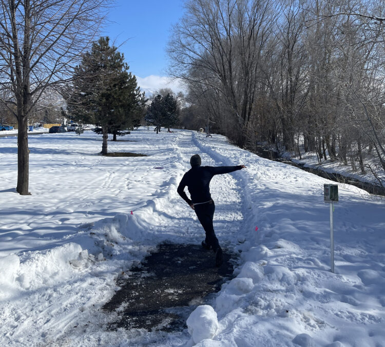 Disc golfer throwing a grippy disc in the snow.
