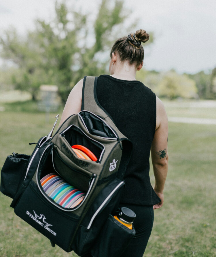 Female disc golfer carrying a bag of discs