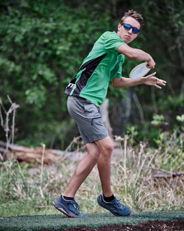 A professional disc golfer throwing an anhyzer shot