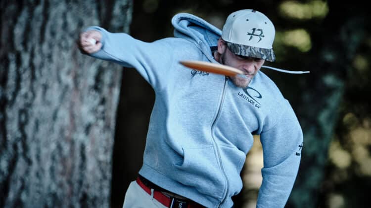A professional disc golfer throwing a disc