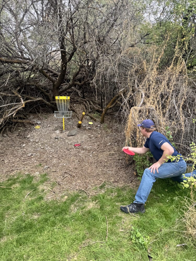 a disc golfer executing a kneeling putt