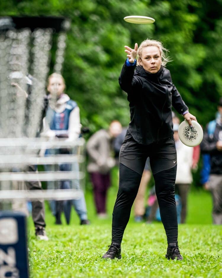 A disc golfer putting with a straddle stance